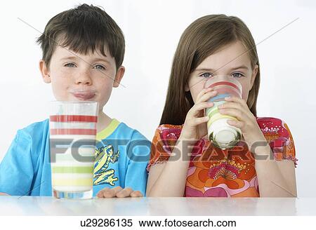 Boy and girl (5-6) sitting at table drinking milk from colourful glasses portrait View Large Photo Image Stock Photography - Boy and girl (5-6) sitting at table drinking milk from colourful glasses portrait. Fotosearch