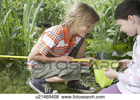 Boy and girl (7-9) looking into fishing net View Large Photo Image Stock Photo - Boy and girl (7-9) looking into fishing net. Fotosearch