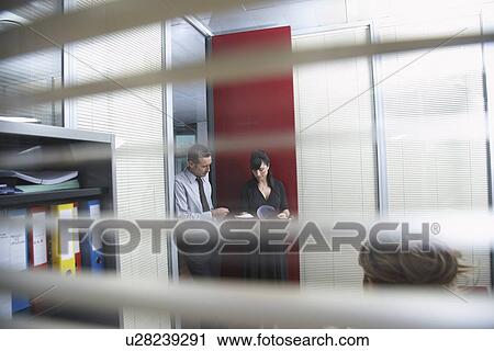 Business colleagues discussing document in office seen through window blinds View Large Photo Image Stock Image - Business colleagues discussing document in office seen through window blinds. Fotosearch