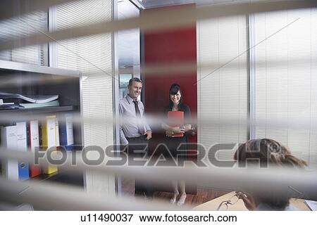 Business colleagues talking in office seen through window blinds View Large Photo Image Stock Photo - Business colleagues talking in office seen through window blinds. Fotosearch