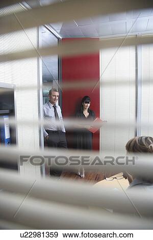 Business colleagues talking in office seen through window blinds View Large Photo Image Stock Photo - Business colleagues talking in office seen through window blinds. Fotosearch
