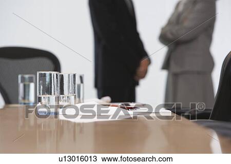 Business couple standing by conference table mid section focus on table View Large Photo Image Stock Image - Business couple standing by conference table mid section focus on table. Fotosearch