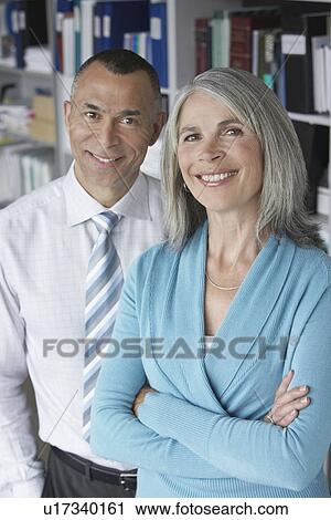 Stock Image - Business couple standing in office portrait elevated view. Fotosearch