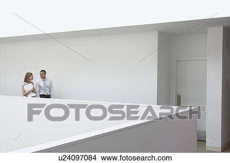 Picture - Business couple walking through office hallway side view. Fotosearch