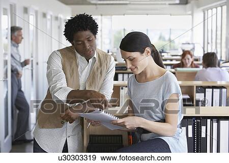 Business man and colleague discussing paperwork in office View Large Photo Image Stock Photo - Business man and colleague discussing paperwork in office. Fotosearch