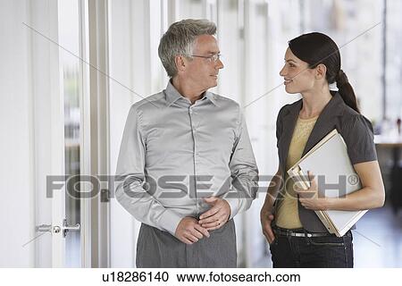 Business man and female colleague talking in office View Large Photo Image Stock Image - Business man and female colleague talking in office. Fotosearch