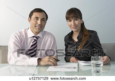 Stock Photo - Business man and woman at table in office portrait. Fotosearch