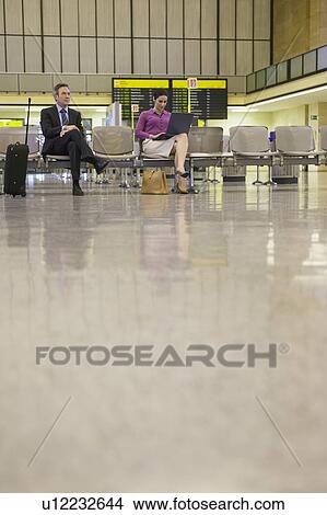 Business man and woman using laptop in airport lobby View Large Photo Image Picture - Business man and woman using laptop in airport lobby. Fotosearch