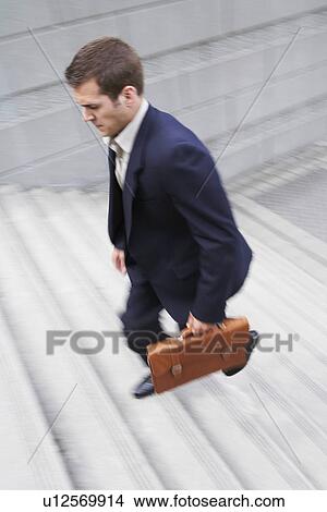 Business man carrying briefcase ascending steps elevated view View Large Photo Image Picture - Business man carrying briefcase ascending steps elevated view. Fotosearch