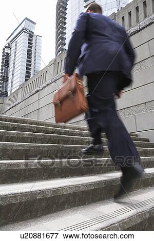Business man carrying briefcase ascending steps low angle view View Large Photo Image Stock Photo - Business man carrying briefcase ascending steps low angle view. Fotosearch
