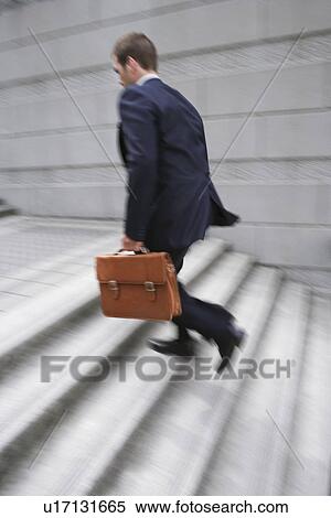 Stock Photography - Business man carrying briefcase ascending steps. Fotosearch