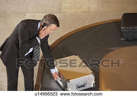 Business man claiming suitcase at luggage carousel in airport View Large Photo Image Stock Image - Business man claiming suitcase at luggage carousel in airport. Fotosearch