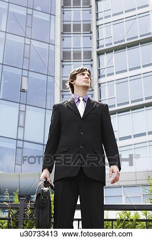 Business man holding briefcase outside office View Large Photo Image Stock Image - Business man holding briefcase outside office. Fotosearch