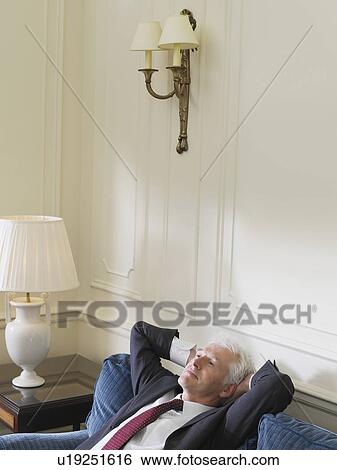 Stock Photograph - Business man leaning back on sofa elevated view. Fotosearch