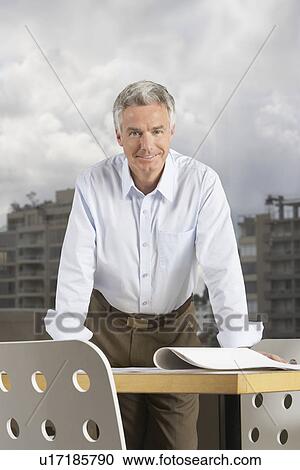 Stock Image - Business man leaning on desk portrait. Fotosearch