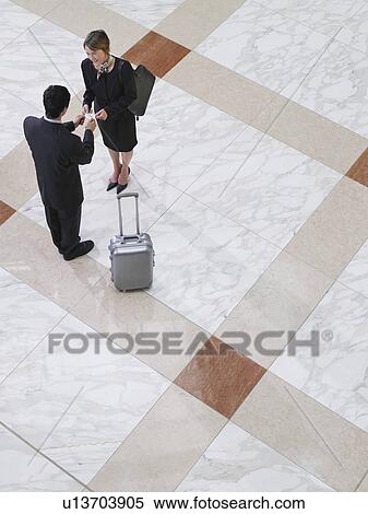 Stock Photography - Business man presenting business card to business woman elevated view. Fotosearch
