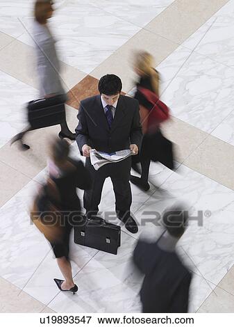 Business man reading newspaper amongst people walking elevated view long exposure View Large Photo Image Stock Photo - Business man reading newspaper amongst people walking elevated view long exposure. Fotosearch