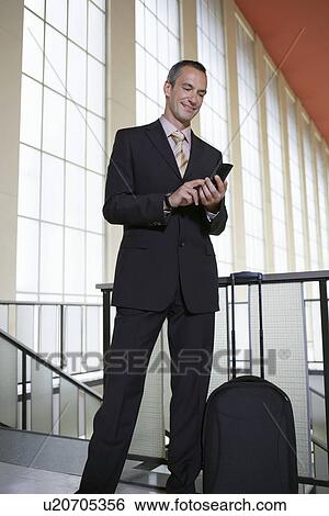 Business man sending text message in airport lobby View Large Photo Image Stock Photograph - Business man sending text message in airport lobby. Fotosearch