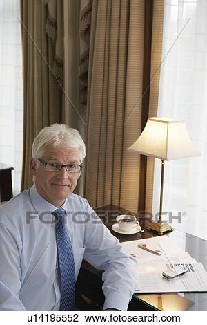 Stock Image - Business man sitting at desk elevated view portrait. Fotosearch