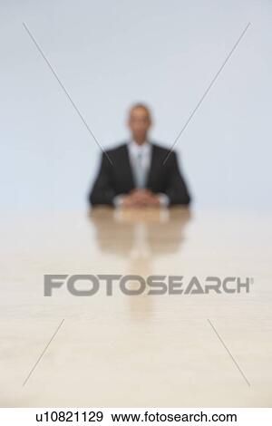 Business man sitting at end of conference table (defocused) View Large Photo Image Stock Photo - Business man sitting at end of conference table (defocused). Fotosearch