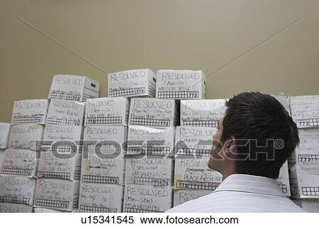 Business man standing in front of stack of filing boxes in storage room back view low angle view View Large Photo Image Stock Photography - Business man standing in front of stack of filing boxes in storage room back view low angle view. Fotosearch
