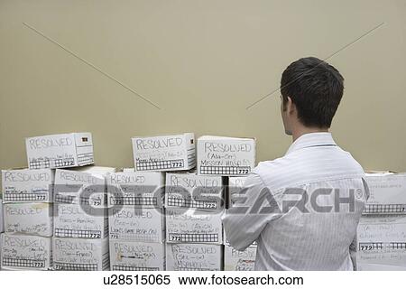 Business man standing in front of stack of filing boxes in storage room back view View Large Photo Image Stock Photography - Business man standing in front of stack of filing boxes in storage room back view. Fotosearch