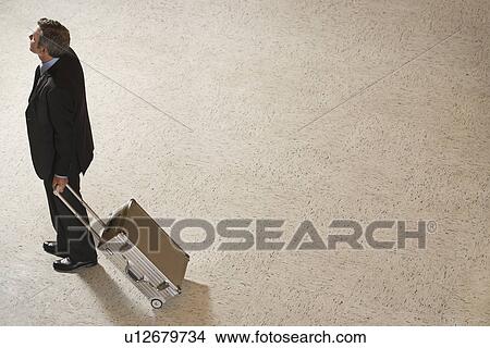 Picture - Business man standing with suitcase in lobby. Fotosearch