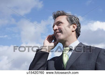 Business man talking on mobile phone outdoors View Large Photo Image Stock Image - Business man talking on mobile phone outdoors. Fotosearch