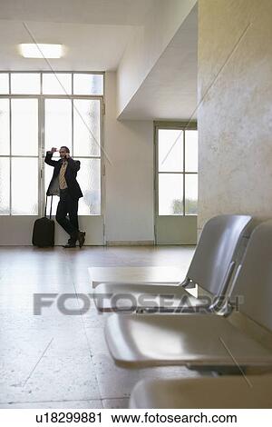 Business man using mobile phone by window in airport View Large Photo Image Stock Image - Business man using mobile phone by window in airport. Fotosearch