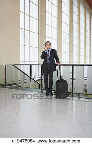 Business man using mobile phone in airport lobby View Large Photo Image Picture - Business man using mobile phone in airport lobby. Fotosearch