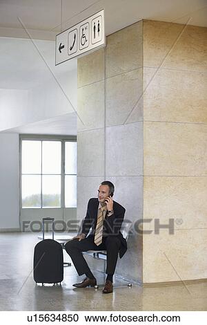 Stock Image - Business man using mobile phone in airport. Fotosearch