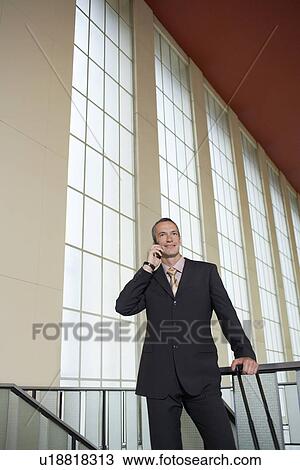 Business man using mobile phone in airport lobby View Large Photo Image Stock Image - Business man using mobile phone in airport lobby. Fotosearch
