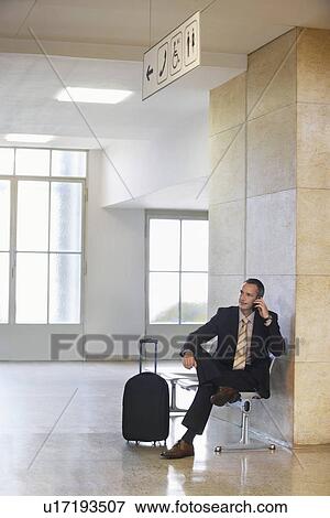 Stock Photo - Business man using mobile phone in airport. Fotosearch