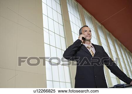 Business man using mobile phone in airport lobby View Large Photo Image Stock Photography - Business man using mobile phone in airport lobby. Fotosearch