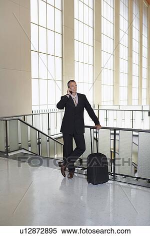 Business man using mobile phone in airport lobby View Large Photo Image Stock Photography - Business man using mobile phone in airport lobby. Fotosearch