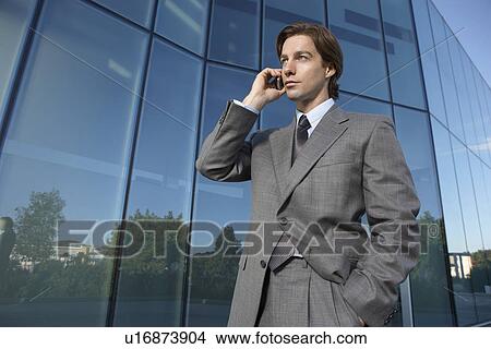 Business man using mobile phone outside office building View Large Photo Image Picture - Business man using mobile phone outside office building. Fotosearch