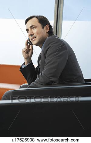 Business man using mobile phone sitting in leather chair in office View Large Photo Image Stock Photo - Business man using mobile phone sitting in leather chair in office. Fotosearch