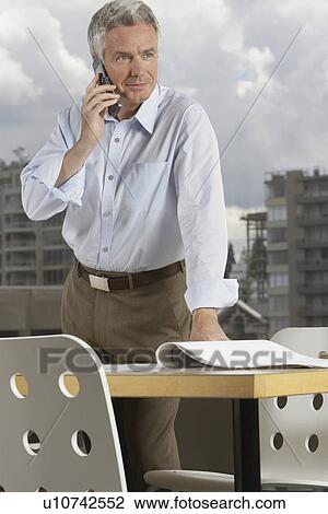 Stock Image - Business man using phone in office. Fotosearch