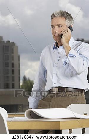 Business man using phone in office View Large Photo Image Stock Photo - Business man using phone in office. Fotosearch