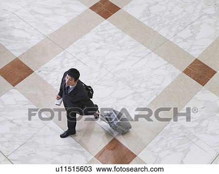 Stock Image - Business man walking with suitcase elevated view. Fotosearch