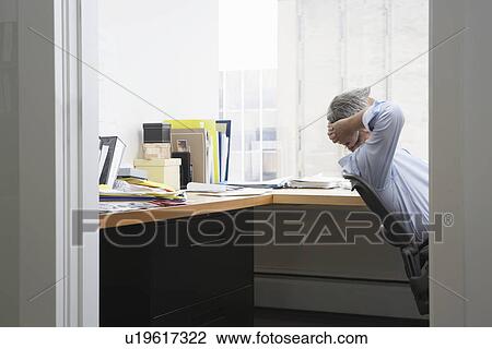Business man with hands behind head in office View Large Photo Image Stock Image - Business man with hands behind head in office. Fotosearch