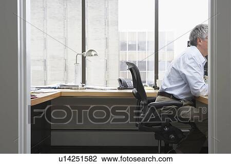 Stock Image - Business man working at desk in office. Fotosearch