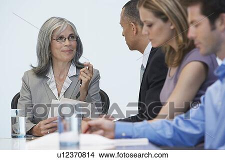 Picture - Business people sitting at conference table. Fotosearch