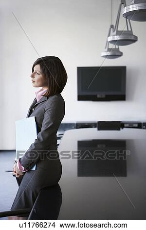 Business woman leaning against table in conference room View Large Photo Image Picture - Business woman leaning against table in conference room. Fotosearch
