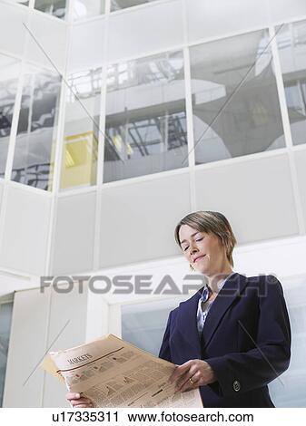 Business woman reading newspaper in atrium of office building low angle view View Large Photo Image Stock Image - Business woman reading newspaper in atrium of office building low angle view. Fotosearch