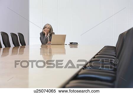 Stock Photography - Business woman sitting by laptop in board room. Fotosearch