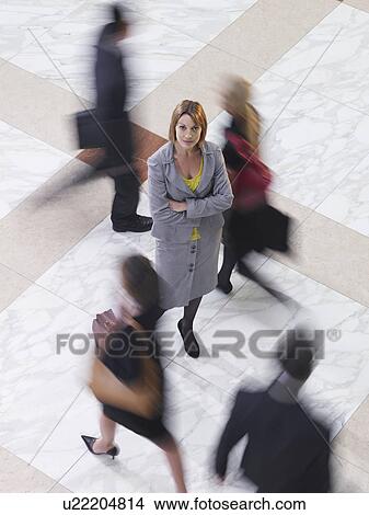 Business woman standing amongst people walking elevated view long exposure View Large Photo Image Picture - Business woman standing amongst people walking elevated view long exposure. Fotosearch