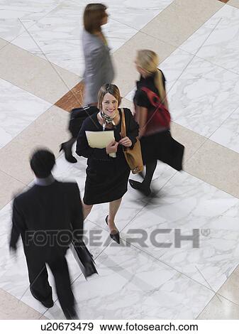 Business woman standing amongst people walking elevated view long exposure View Large Photo Image Stock Photo - Business woman standing amongst people walking elevated view long exposure. Fotosearch