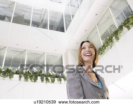 Business woman standing in atrium of office building low angle view View Large Photo Image Stock Photo - Business woman standing in atrium of office building low angle view. Fotosearch