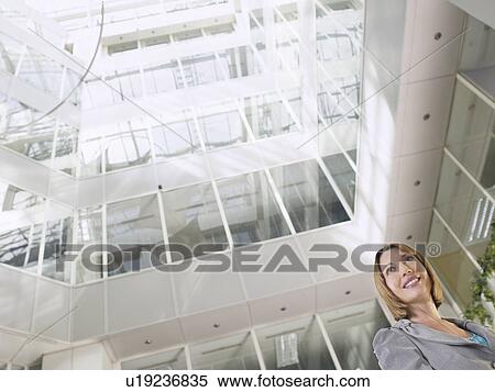Business woman standing in atrium of office building low angle view View Large Photo Image Stock Photography - Business woman standing in atrium of office building low angle view. Fotosearch